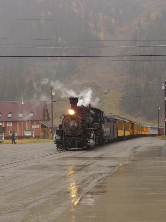 a steam train makes its way down the track in the rain