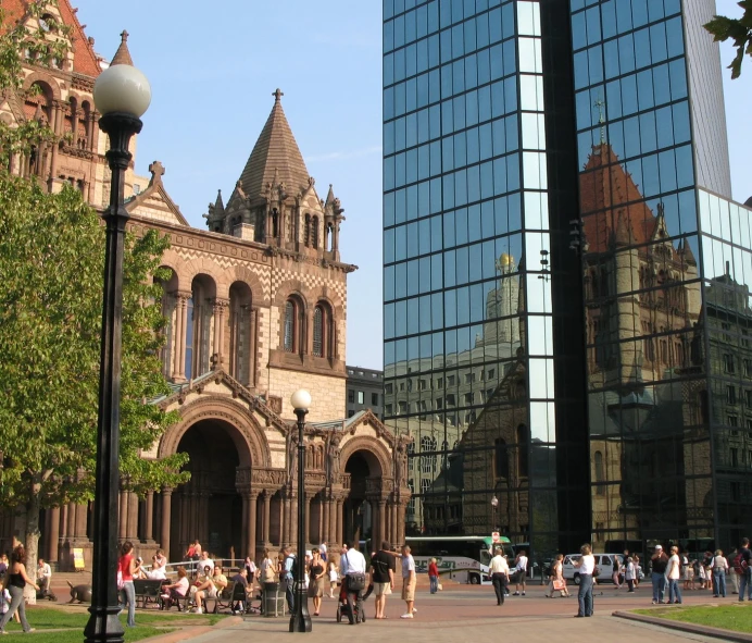 several people walk in a city square next to tall buildings