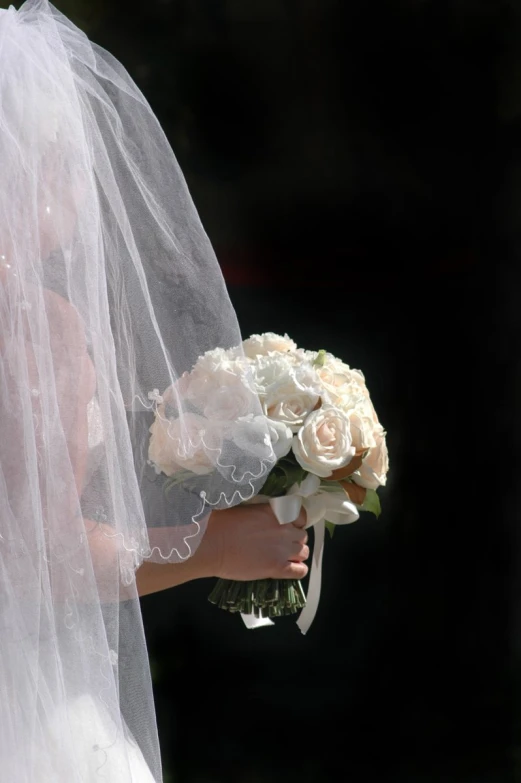 a white bridal is holding flowers near her dress