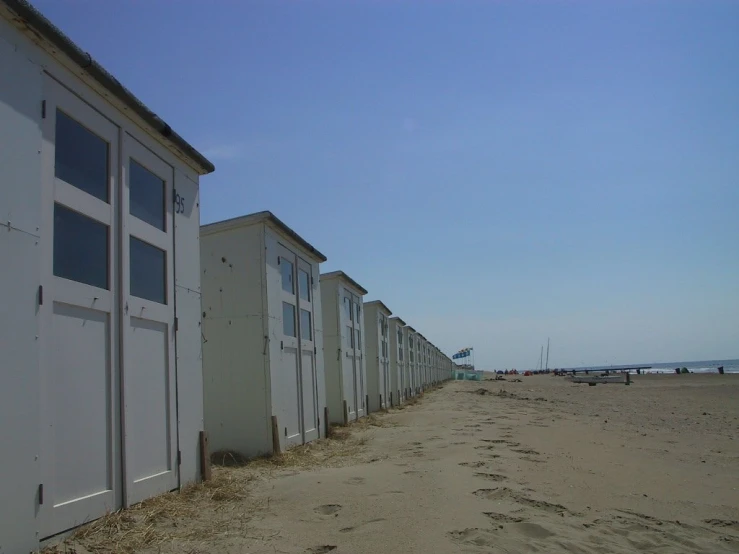 an empty beach next to a row of white beach huts