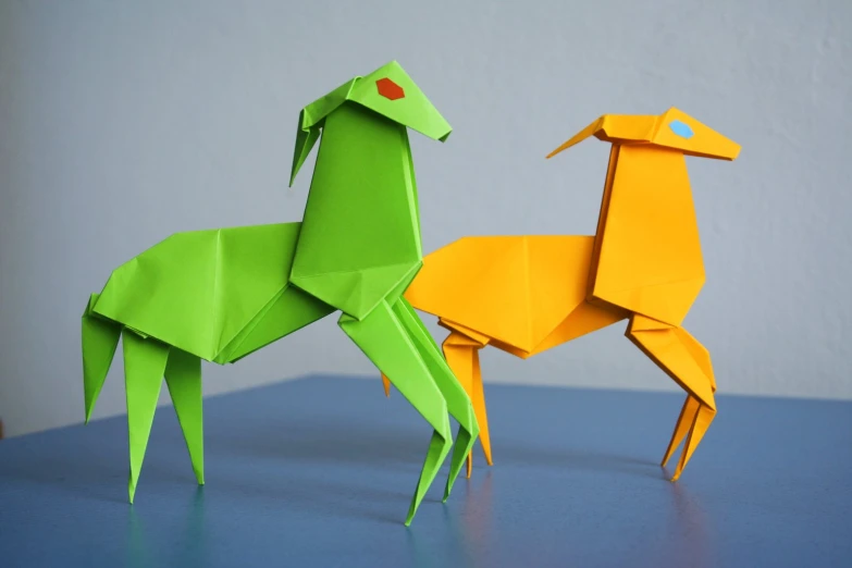 two different colored paper animals sitting on top of a table