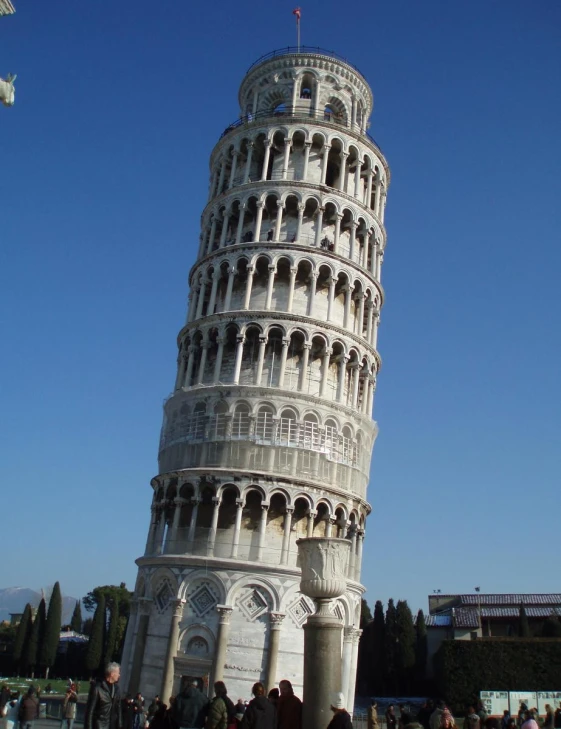 a very tall leaning tower with people near by