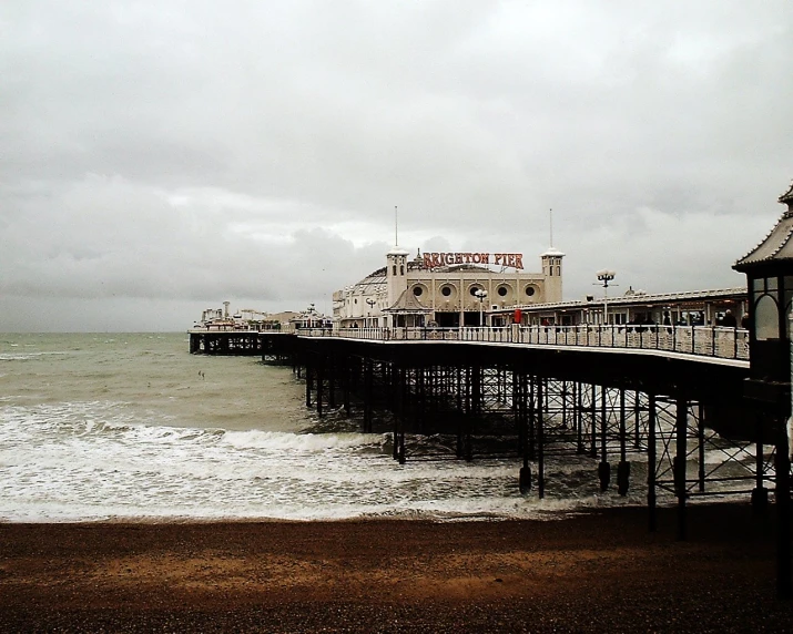 the ocean next to a long pier with a row of buildings