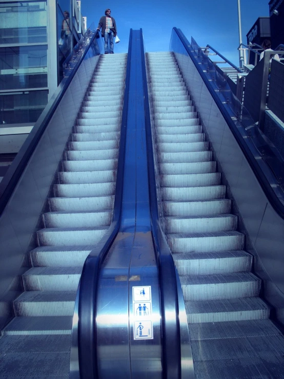 two people are standing at the top of an escalator