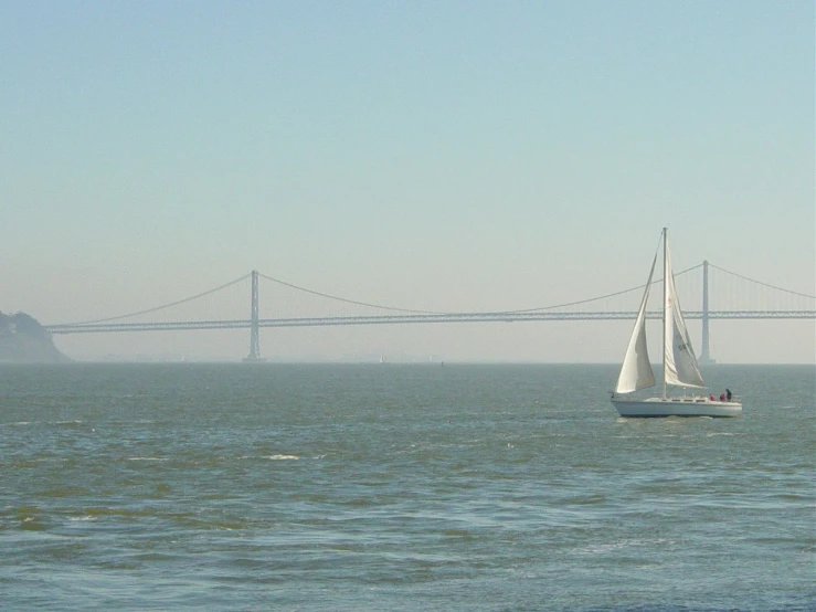 a boat sailing on water near bridge and hills