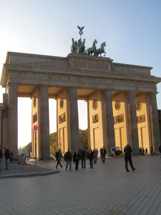 people walking in front of a large white arch