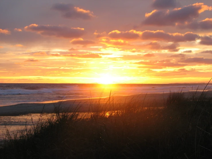 sun setting on the beach over a body of water