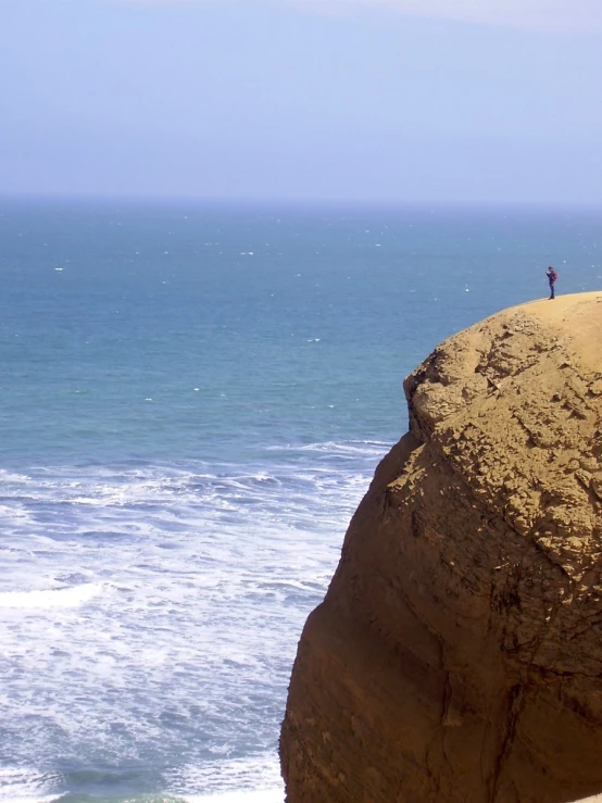 three people on rocks looking out to the ocean