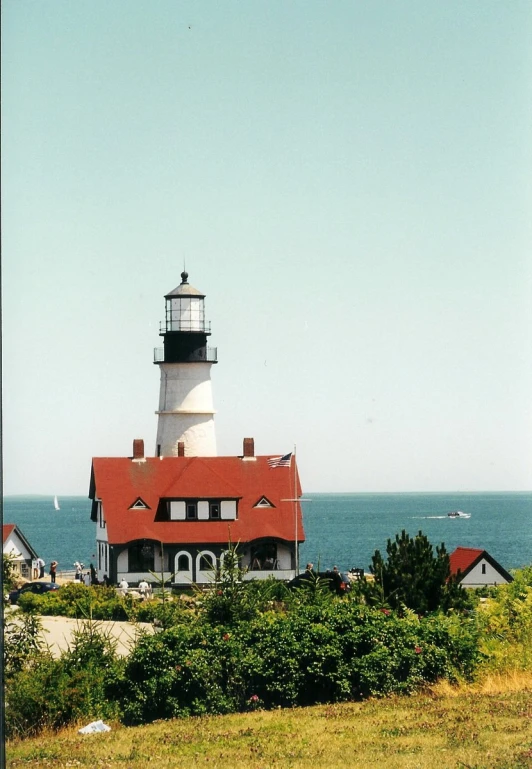a lighthouse with two red roofs on top of a green hillside