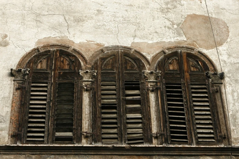 four wooden windows set on side of old brick building