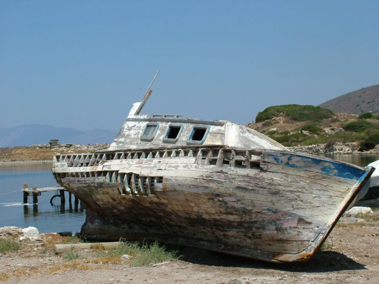 an abandoned boat with water and rocks in the background