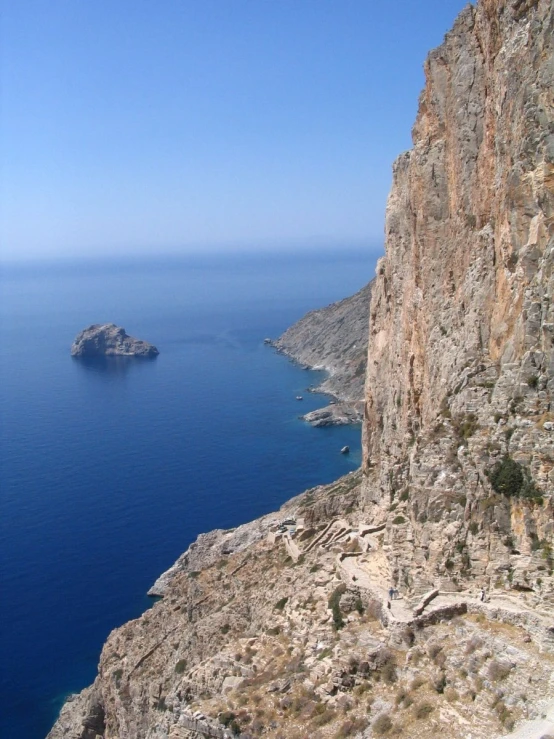 a big cliff by the ocean and some rocks