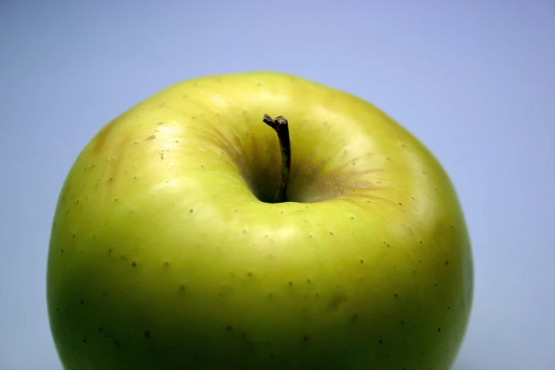 the top part of a green apple against a blue background