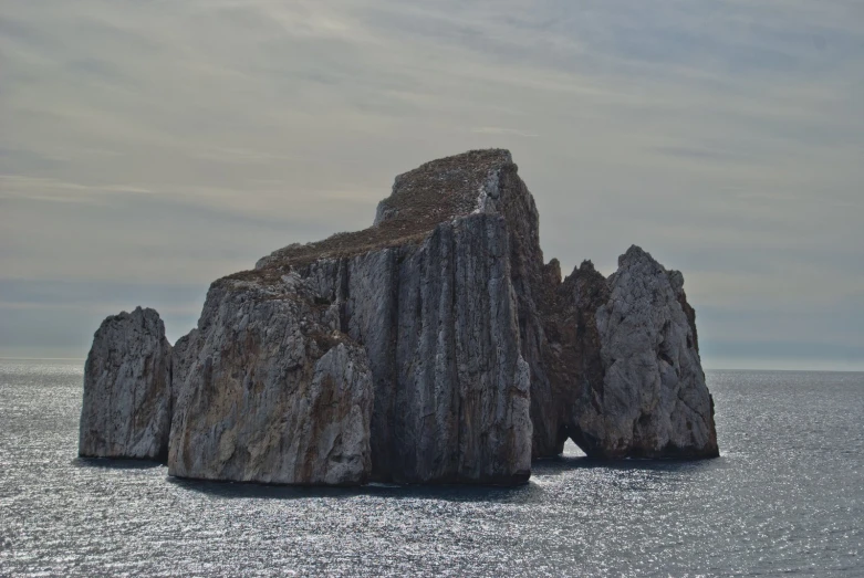 rocks sticking out of the ocean on a cloudy day