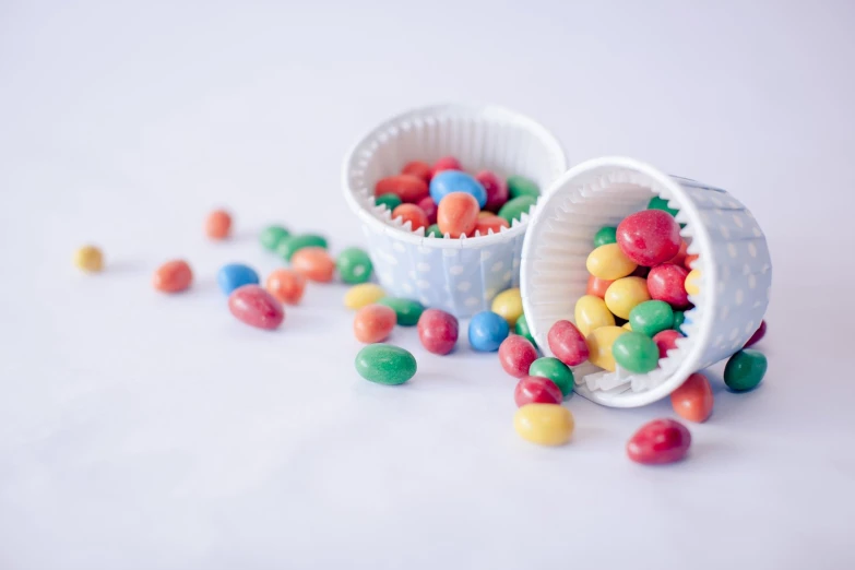 two cups filled with jelly beans on top of white surface