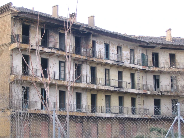 an old building with broken windows in front of a chain link fence