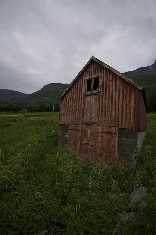 a red wooden shed sitting in a green field