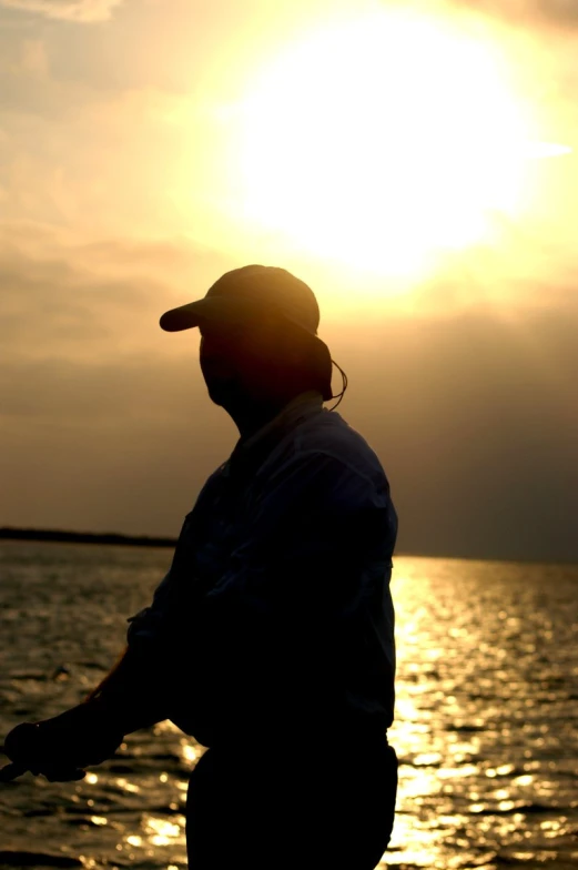 a person looking out at the water with the sun in the background