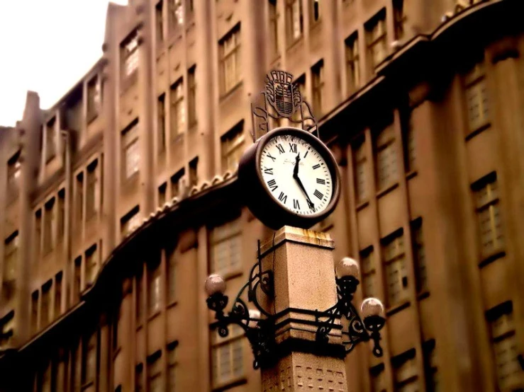 a clock on top of a post in front of some buildings