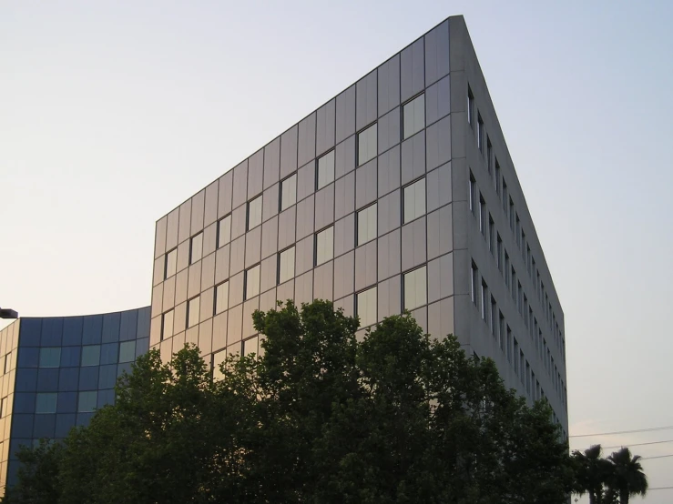 a grey building is seen near several trees