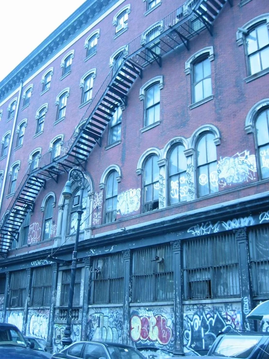 a very tall red brick building with graffiti and a fire escape