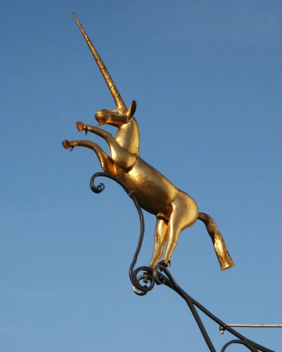 a golden sculpture depicting an unicorn is on top of a building