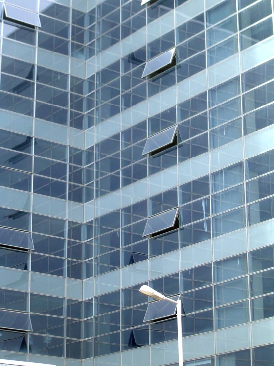 this glass building has five street lamps in the foreground