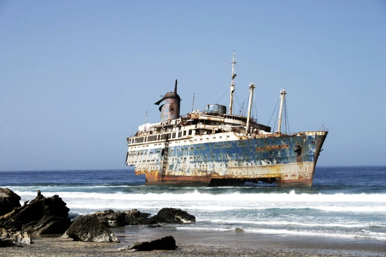 there is a large rusty boat that is on the beach