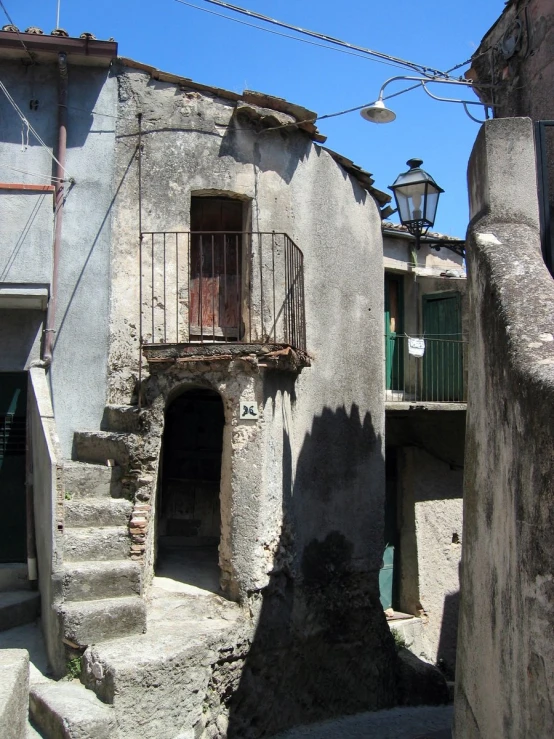 an alley with stone buildings and stairs leading up to balconies