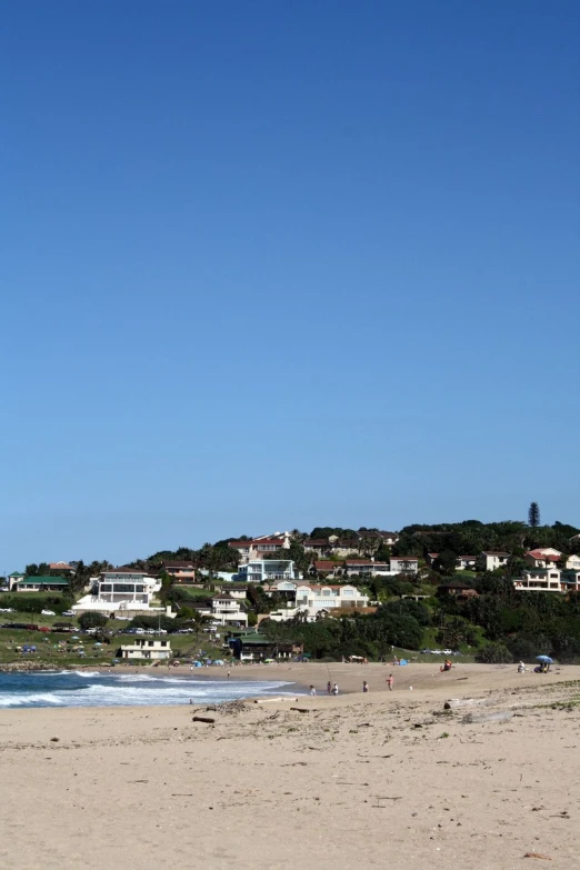 a large white beach with houses on a hill on top