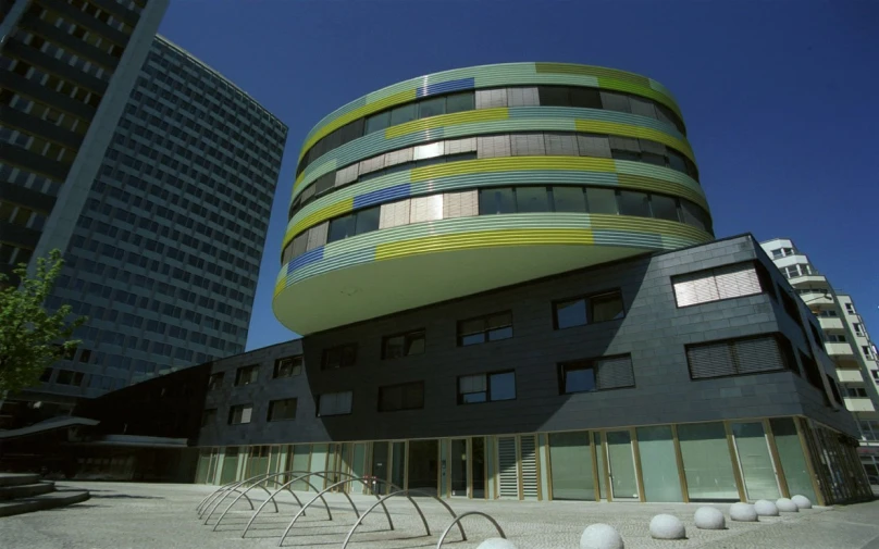 a curved building in a city next to tall buildings