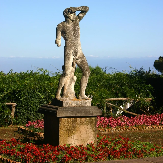 a statue of a  man stands in a garden