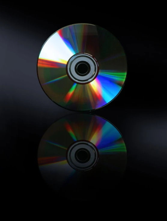 a cd with rainbow colors is shown on a black surface