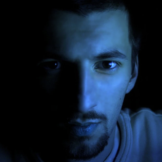 man with dark face looking directly at the camera