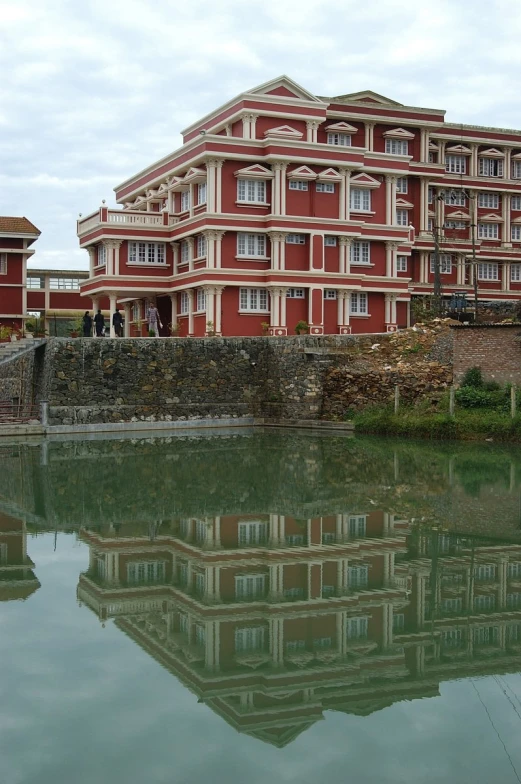 a building with a clock tower and three levels of windows on top is reflected in water