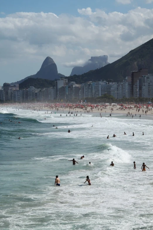 many people are in the ocean and on the beach