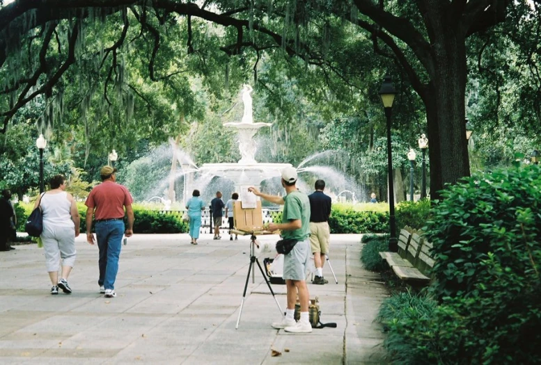 a group of people standing around with a fountain behind them