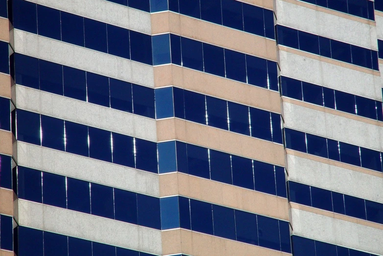 an airplane flying by some building with blue windows