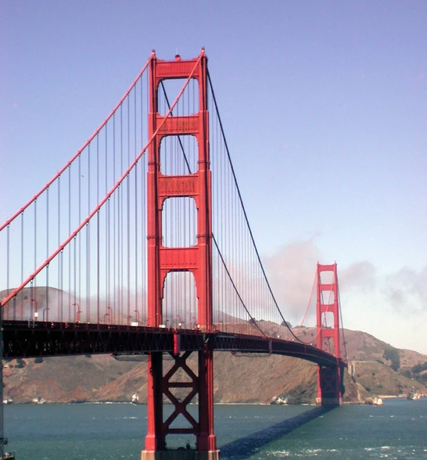 a large suspension bridge over the ocean on a sunny day