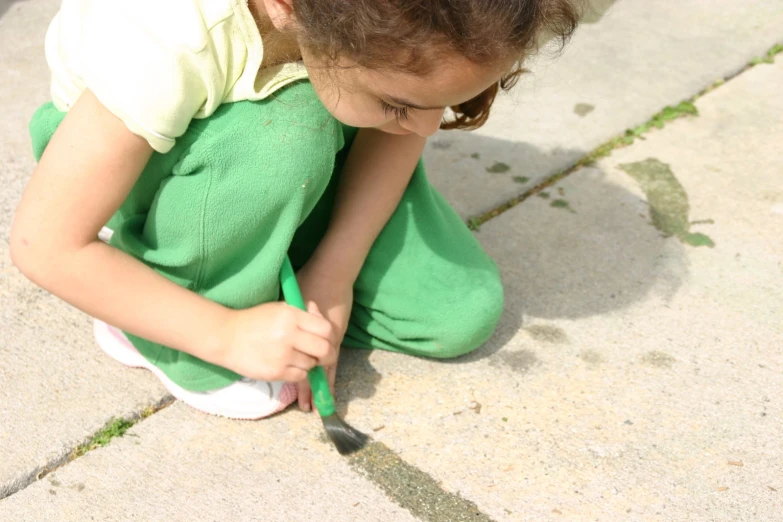 a child sitting on the ground, drawing soing in it