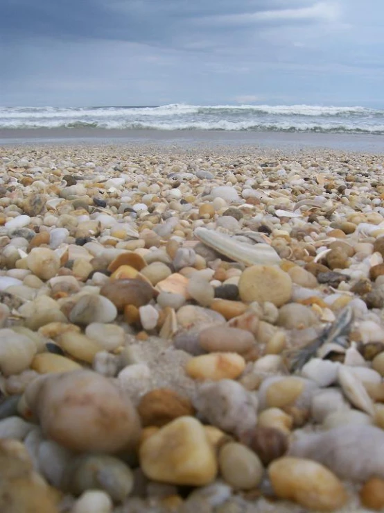 rocks scattered on the shore near water under an overcast sky