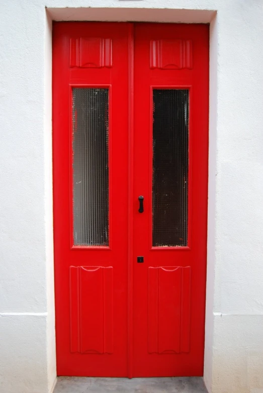 a red door with a white wall and two side lit lights