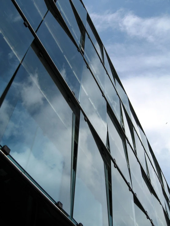 a building is made of glass and reflecting clouds