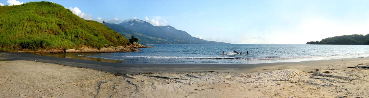 three people surfing out in the ocean near mountains