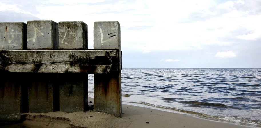 an old wooden structure on a sandy beach