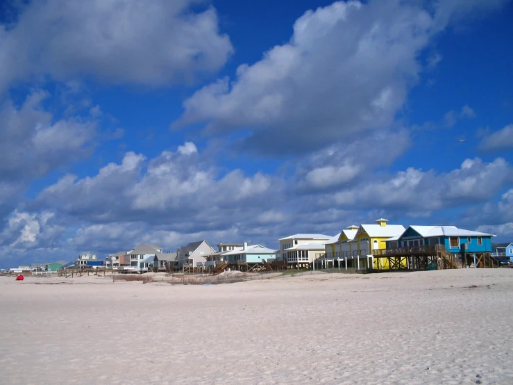 the white sand of an empty beach covered in houses