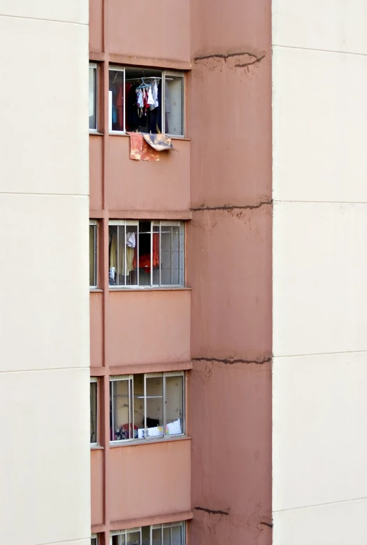 a man who is sitting in the windows of a pink building