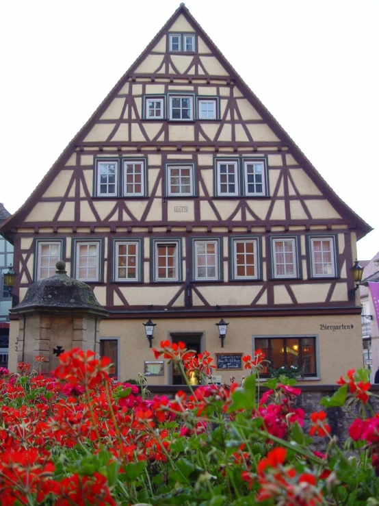 flowers surround a bed of greenery in front of a large building