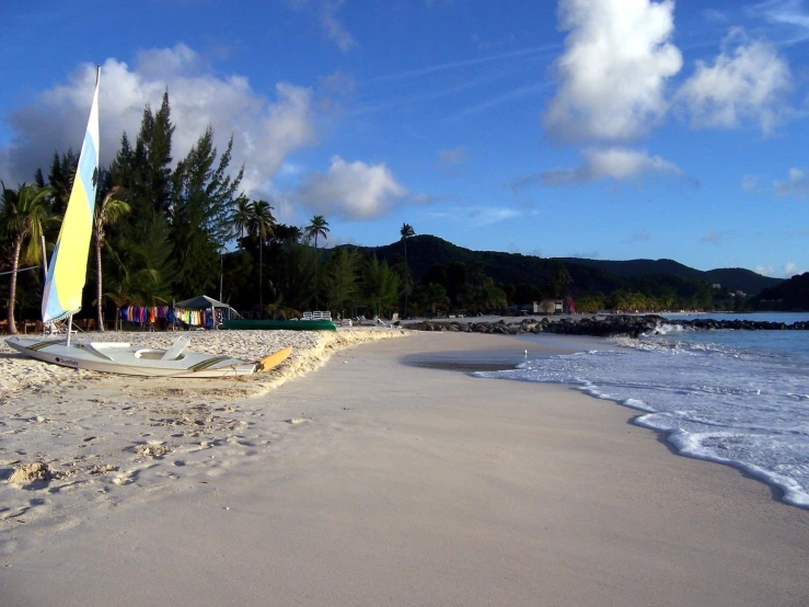 a boat sits on the sand on a tropical beach