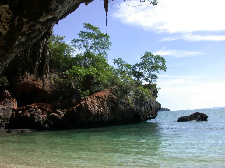 a cliff with clear blue water on the shoreline